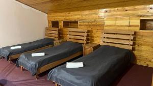 three beds in a room with wooden walls at Argishti Hotel in Vanadzor