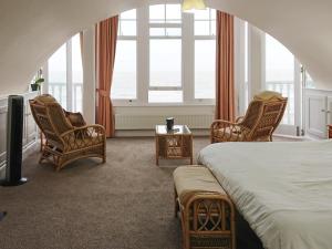a bedroom with a bed and chairs and windows at Seascape in Ramsgate