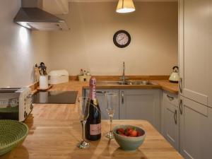 a kitchen with a bottle of wine and a bowl of fruit at Gardeners Cottage in Mudford