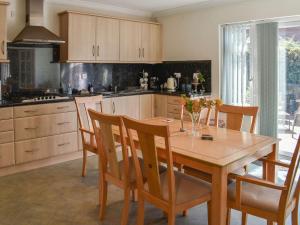 a kitchen with a wooden table with chairs and a dining room at Squires Bungalow in Gunton