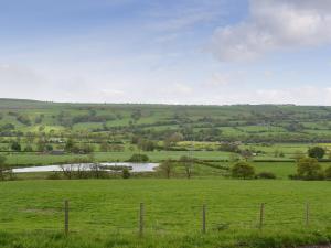 a field of green grass with a river in the distance at The Farm House in Wolsingham