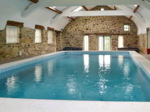 a large swimming pool in a building with a brick wall at The Farm House in Wolsingham