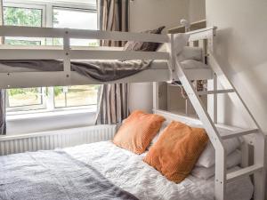 a bunk bed with two orange pillows and a ladder at Bay House in Canterbury