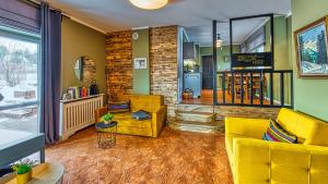 ein Wohnzimmer mit gelben Möbeln und einer Ziegelwand in der Unterkunft Apartamenty ROYAL APARTS Zielona Poręba - z panoramą gór in Szklarska Poręba