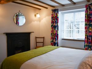 een slaapkamer met een bed, een open haard en een spiegel bij The Snug in Kirkby Lonsdale