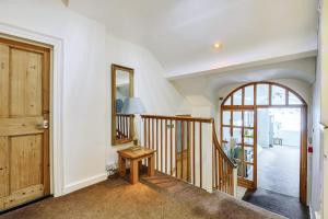 a hallway with a staircase and a mirror and a door at The White House Guest House in Williton