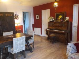 a living room with a piano and a table and chairs at Chambre d'hôtes La Maison du Neuilly in Le Conquet