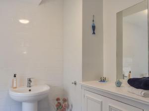 Baño blanco con lavabo y espejo en The Cottage Highfield en Rothbury