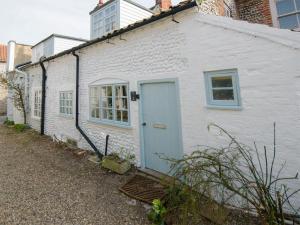 a white house with a blue door on a street at Buttercup Cottage - Ukc2847 in Blakeney