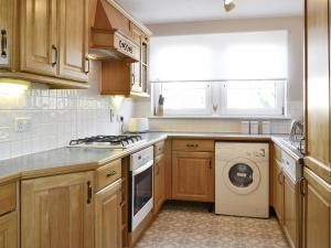a kitchen with wooden cabinets and a washing machine at Powderhall Brae in Edinburgh