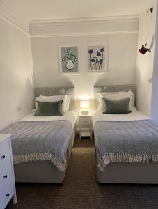 1 dormitorio con 2 camas y mesa con lámpara en The Dozy Deer, en Windermere