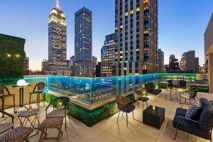 a rooftop patio with tables and chairs and a city skyline at Hyatt Centric Midtown 5th Avenue New York in New York