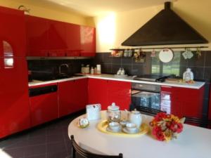 フチェッキオにあるLa Casa di Agata Deluxeのキッチン(赤いキャビネット、白いテーブル、皿付)