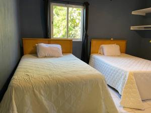 2 camas en una habitación con ventana en casa de campo, en San Juan Tecomatlán