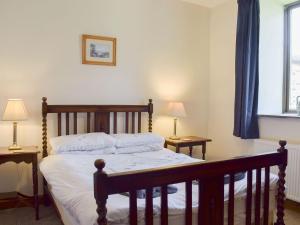 1 dormitorio con 1 cama de madera, 2 mesas y 2 lámparas en Grisedale Coach House en Threshfield