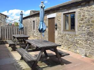 two picnic tables with umbrellas sitting outside of a building at Grisedale Coach House in Threshfield