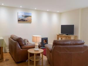a living room with two leather couches and a tv at Gardeners Lodge in Pembroke