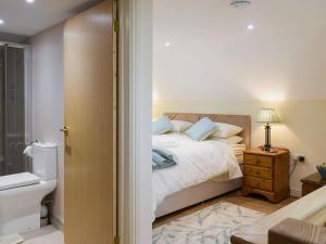 a bedroom with a bed and a bathroom with a toilet at Gardeners Lodge in Pembroke
