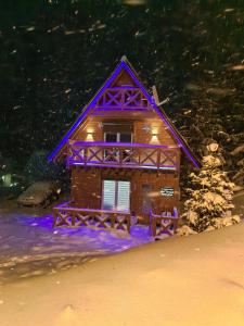 una pequeña casa en la nieve por la noche en Planinska kuca NATURA en Vlasic