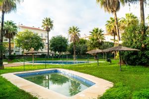 una piscina en un parque con palmeras en R&B Vistahermosa Garden, en El Puerto de Santa María
