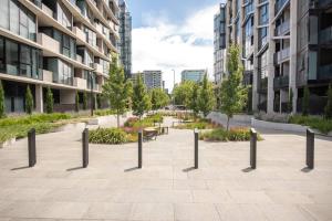 a courtyard in a city with benches and trees at Luxury modern CBD ground floor apartment. in Canberra