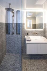 a bathroom with a shower and a sink and a mirror at Luxury modern CBD ground floor apartment. in Canberra