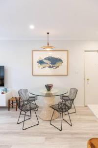 a dining room with a glass table and chairs at Luxury modern CBD ground floor apartment. in Canberra