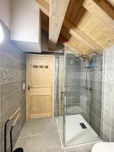 a bathroom with a shower and a wooden door at Chalet Le Gebroulaz in La Toussuire