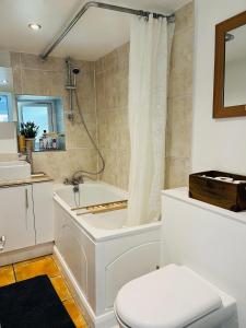 a bathroom with a white tub and a toilet at Lavender Den in London