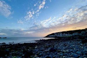 a rocky beach at sunset with a cloudy sky at Spacious home with panoramic sea view, free parking EV & large garden in Mousehole