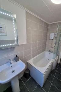 a bathroom with a sink and a tub and a toilet at Spacious home with panoramic sea view, free parking EV & large garden in Mousehole