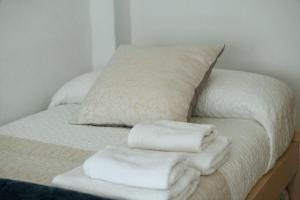 Una cama con toallas blancas apiladas encima. en A Solaina en Redondela