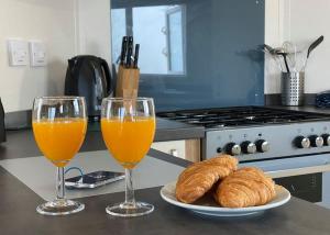 two glasses of orange juice and croissants on a kitchen counter at Lynmouth Holiday Retreat in Lynton