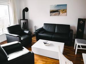a living room with black leather furniture and a coffee table at Gemütliches Ferienhäuschen an der Schlei & Ostsee in Maasholm