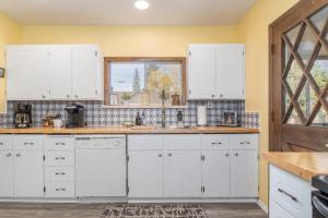 a kitchen with white cabinets and a window at Rockwell Retreat by NW Comfy Cabins in Leavenworth
