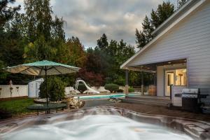 a swimming pool with an umbrella next to a house at All Seasons Getaway by NW Comfy Cabins in Leavenworth