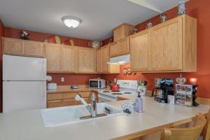 a kitchen with wooden cabinets and a white refrigerator at Suite Serenity Condo by NW Comfy Cabins in Leavenworth