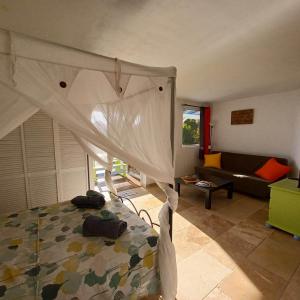 a bedroom with a canopy bed and a couch at Ti coin de paradis Ylang Ylang in Le Diamant
