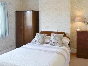 een slaapkamer met een wit bed en een houten kast bij The Castaway in Mundesley