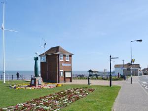 a building with flowers in the grass next to the ocean at The Castaway in Mundesley