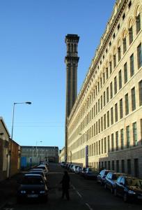 una persona caminando por una calle al lado de un edificio en Lister Mills, Apartment 327, Silk Warehouse, Lilycroft Rd, BD9 5BD en Bradford