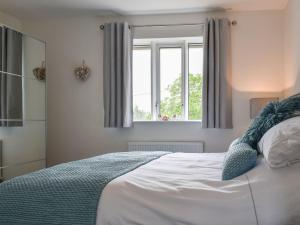 a bedroom with a large white bed with a window at Mills Croft in Hognaston