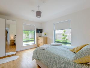 a bedroom with a large bed and two windows at Rosedene in Freshwater