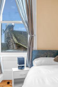 愛丁堡的住宿－Edinburgh City Centre Jasmine Apartment -SLEEPS 7，一间卧室设有一张床和一个带电视的窗户。