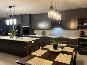 una cocina con armarios negros y una mesa de madera con sillas. en Sea Winds Bungalow - Tierra Del Sol Aruba, en Noord