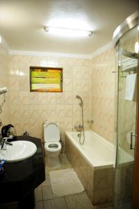 a bathroom with a toilet and a tub and a sink at Stipphotels, Kiyovu in Kigali