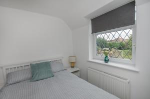 a white bedroom with a bed and a window at Hideaway Cottage in Bristol