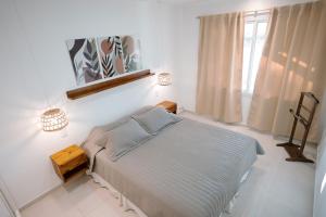 a white bedroom with a bed and a window at Cabaña 1920 - frente a viñedo in San Rafael