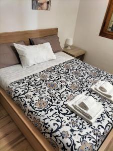 a bed with a black and white comforter with two towels on it at L'incanto home in Bologna