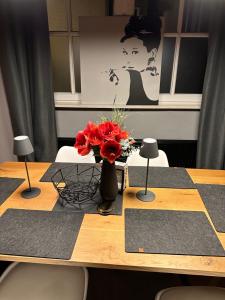 una mesa con un jarrón de flores rojas. en Loft mit privater Sauna en Heidelberg